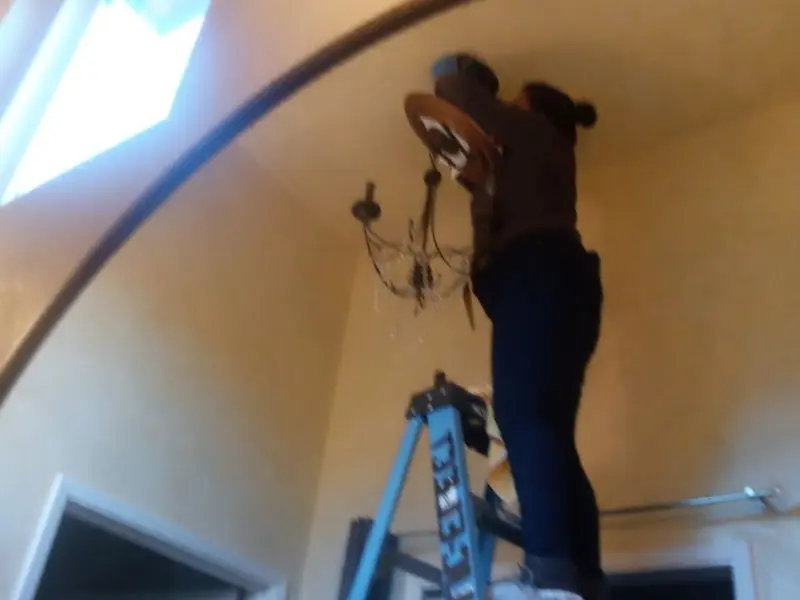 Electrician installing a chandelier in a Montgomery residence